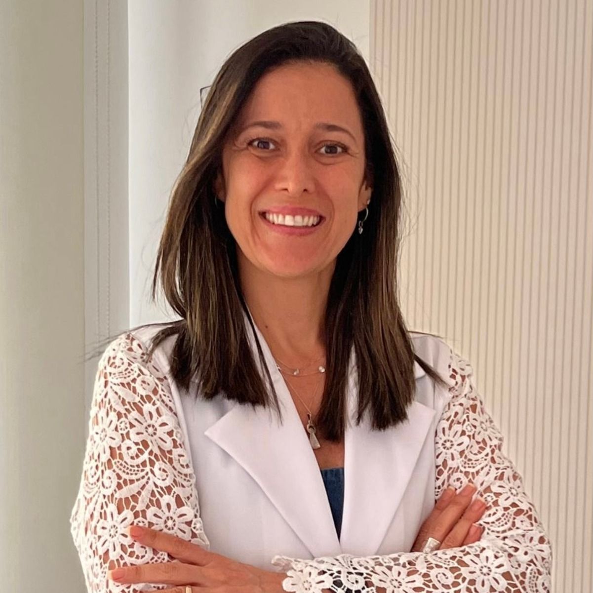 Christiana de Oliveira sorrindo, de jaleco branco